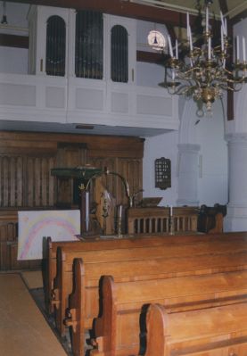 Hervormde-Kerk
Gezicht op de kansel lezenaar in de vorm van de adelaar, vanouds symbool van het Woord.
De aan de kansel gehechte doopvont en de koperen boog boven het hek Het jaartal op de boog is 1676.
