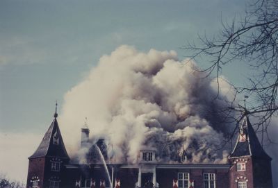 Brand-kasteel-Nederhorst
Enorme rookwolken hangen boven het fel brandende kasteel nadat de brand door het dak is geslagen; brandweerlieden klimmen met de brandslang naar binnen over het balkon aan de voorzijde van het kasteel.
Trefwoorden: Brand; brandweer; kasteel;