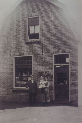 Tinus-Vlaanderen-voor-zijn-Vege-winkel
Tinus Vlaanderen met echtgenote en kind voor zijn Végé kruidenierswinkel.
Op de borden op de muur staan Blue Band, Bernsens koffie, Mir Moccona.

